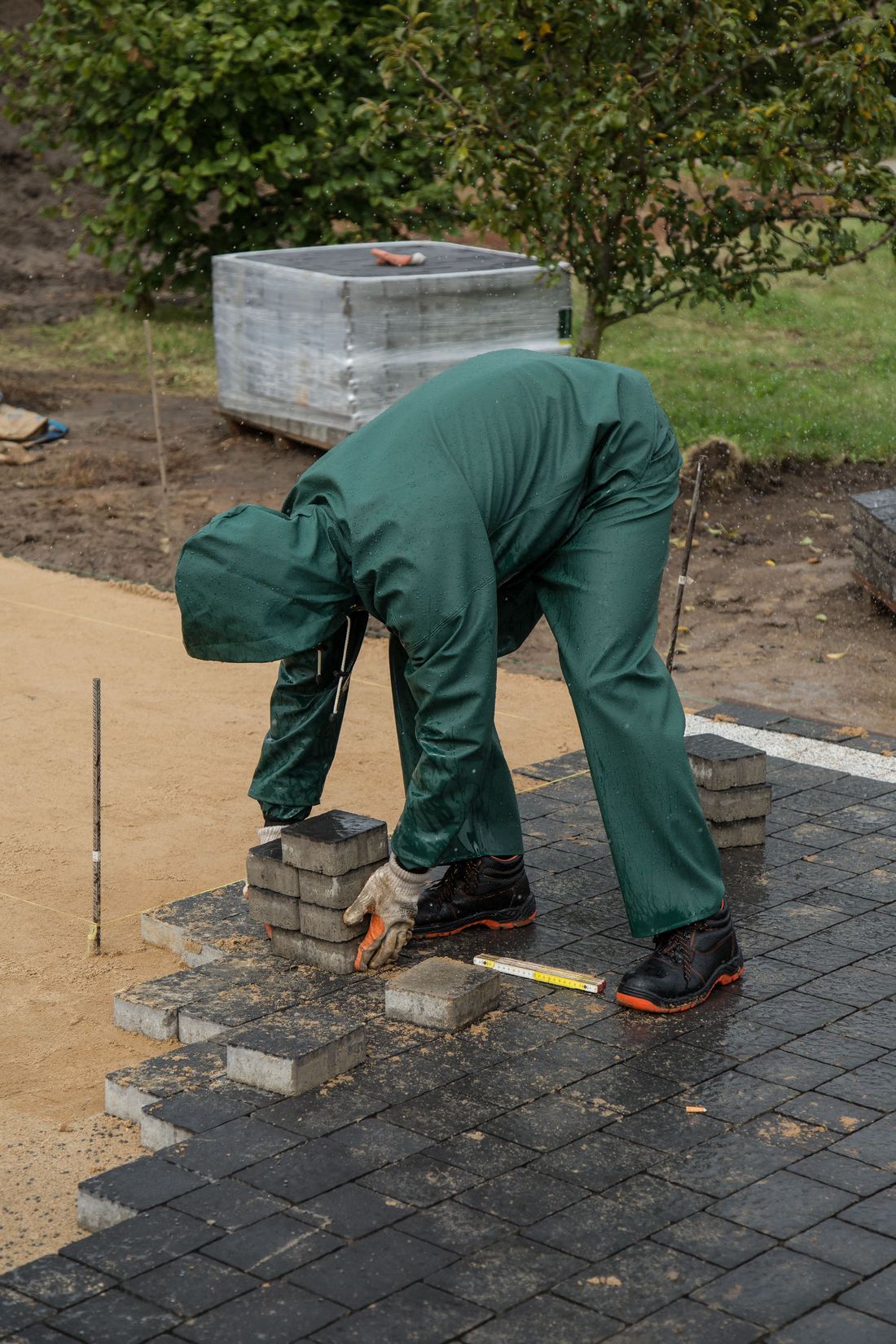 A worker in safety boots laying paving blocks