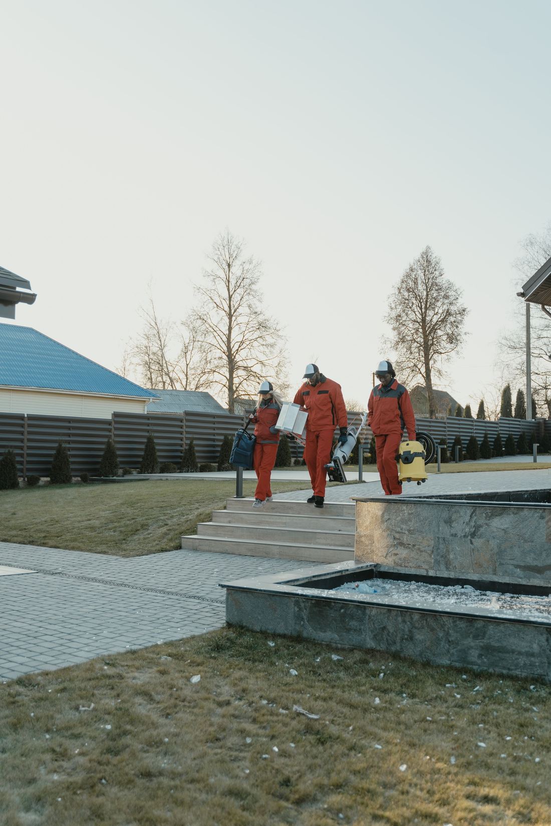 A uniformed team carrying equipment across a property