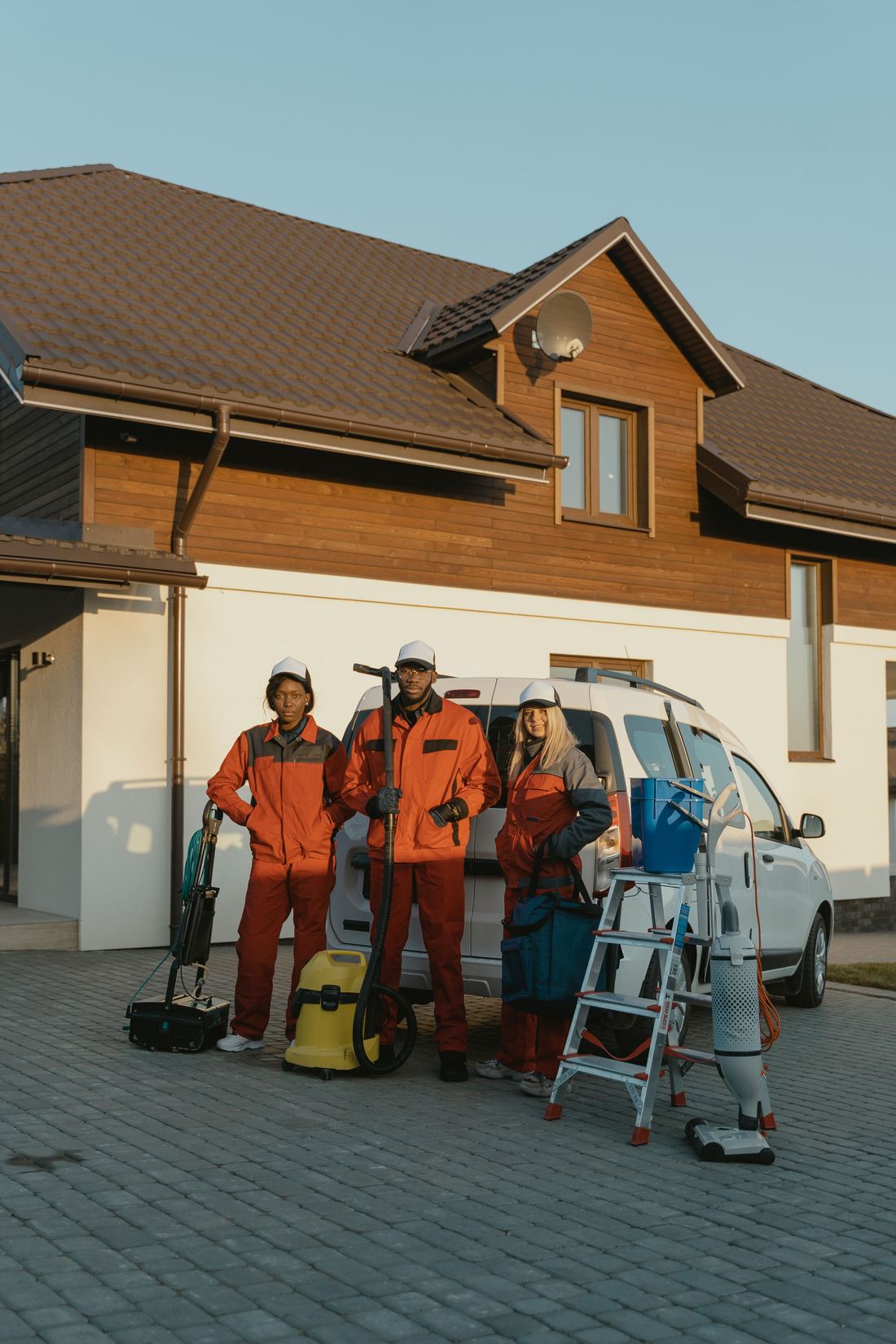 A uniformed cleaning team standing beside their vehicle with cleaning equipment